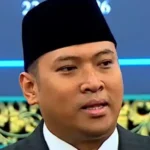 Beritagosip.com - Seorang petugas pemerintah tinggi memutuskan untuk keluar membela program Makan Bergizi Gratis (MBG) dari berbagai kritik yang menyebut bahwa inisiatif nutrisi itu menghabiskan anggaran negara dan menyebabkan perbaikan infrastruktur sekolah tertunda. Kepala Badan Gizi Nasional (BGN) Sudaryono menghadapi tugas yang tidak mudah ketika viralnya sebuah foto menampilkan siswa-siswi dari sekolah dasar SDN Tanggirejo yang terletak di Grobogan, Jawa Tengah, sedang menikmati porsi MBG mereka di depan ruang kelas dengan atap yang dalam kondisi sangat rusak dan mengkhawatirkan. Dengan data dan fakta di tangannya, Sudaryono melakukan klarifikasi publik yang tegas. Pemerintah, demikian pengakuannya, sebenarnya terus-menerus meningkatkan skala program revitalisasi infrastruktur sekolah bahkan ketika program MBG sedang berjalan penuh. Bukti konkret itu dapat dilihat dari pencapaian pemerintah pada tahun 2025 lalu. Pemerintah telah berhasil merenovasi dan memperbaiki lebih dari 16.000 unit sekolah di seluruh nusantara. Angka yang lebih impresif lagi terungkap untuk target tahun ini, di mana pemerintah menargetkan perbaikan pada lebih dari 70.000 satuan sekolah, dengan beberapa pejabat senior bahkan mengindikasikan bahwa target itu bisa melonjak hingga mendekati angka 90.000 sekolah. "Tahun ini yang mau direnovasi itu lebih dari 70 ribu, bahkan Pak Mendikdasmen pernah mengutarakan bisa jadi hampir 90 ribu sekolah. Yang itu langsung dari pemerintah pusat," ungkap Sudaryono saat ditemui di kantor kerjanya pada Rabu (29/7). Narasi yang terus berkembang di masyarakat bahwa dana negara seluruhnya terkuras habis karena MBG, kata Sudaryono, tidak selaras dengan situasi lapangan yang sebenarnya. Justru, berbagai inisiatif strategis pemerintah terus berjalan bersamaan tanpa terjadi pengurangan signifikan. "Kan ada semacam anggapan bahwa anggaran negara ini habis karena MBG. Pada kenyataannya ada MBG, yang dulu pupuk tidak cukup, sekarang pupuknya cukup. Bahkan harganya didiskon 20 persen," imbuhnya, menunjukkan bahwa program subsidi pertanian juga malah mengalami peningkatan, bukan penurunan. Sudaryono melanjutkan dengan menunjukkan contoh lain dari program-program lain yang juga tetap mengalami peningkatan pembiayaan. Program revitalisasi sistem irigasi pertanian, misalnya, mendapat porsi anggaran yang juga terus bertambah. Pada tahun yang lalu, alokasi untuk irigasi mencapai Rp12 triliun, kemudian naik menjadi Rp14 triliun pada tahun sekarang, dan diproyeksikan akan terus meningkat pada tahun-tahun mendatang. Dalam penjelasannya lebih lanjut, Sudaryono menjauhkan dugaan bahwa keadaan sekolah-sekolah rusak merupakan hasil langsung dari kehadiran program MBG. Kerusakan infrastruktur sekolah sudah ada jauh sebelum MBG diluncurkan sebagai kebijakan publik. "Dulu enggak ada MBG, sekolah itu rusak memang sebelum ada program MBG. Ini sekarang oleh Presiden (Prabowo Subianto) diperbaiki," katanya dengan nada yang menekankan tanggung jawab historis. Untuk menyikapi masalah sekolah yang masih dalam kondisi rusak, Sudaryono mengundang masyarakat luas untuk secara aktif melaporkan setiap satuan pendidikan yang mereka temukan dalam kondisi tidak layak. Pemerintah telah menyediakan saluran pengaduan resmi melalui Kementerian Pendidikan Dasar dan Menengah untuk memudahkan proses pelaporan. "Kalau ada sekolah rusak yang ditemukan itu cukup lapor. Ada portalnya di Dikdasmen, pasti diperbaiki," jelasnya dengan keyakinan bahwa sistem yang ada sudah responsif terhadap keluhan publik. Terakhir, Sudaryono mendesak masyarakat agar tidak lagi membandingkan atau membandel-bandingkan program MBG dengan kondisi infrastruktur sekolah. Kedua inisiatif itu, jelasnya, merupakan program yang terpisah sama sekali dengan mekanisme pembiayaan yang juga berbeda satu sama lain. "Dapur MBG ini yang bangun adalah mitra, sementara perbaikan sekolah ini dua hal yang berbeda," pungkasnya, menekankan perbedaan fundamental dalam struktur dan implementasi kedua program tersebut.