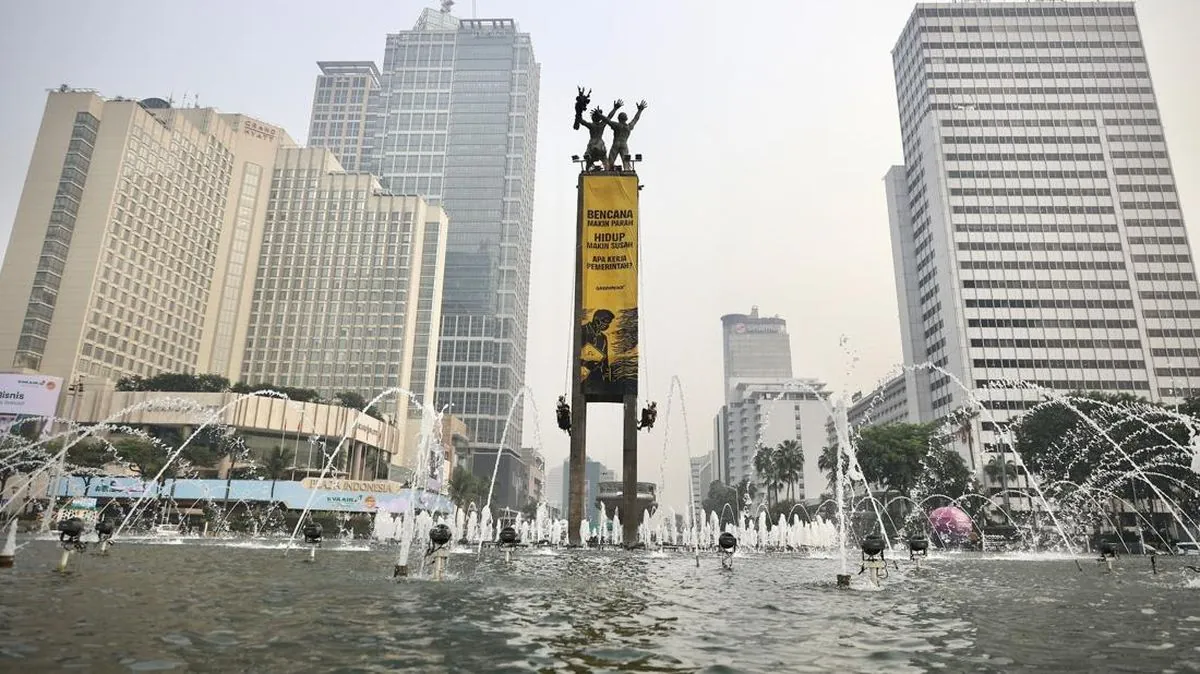 Aktivis Greenpeace Bundaran HI membentangkan spanduk protes krisis iklim di Patung Selamat Datang